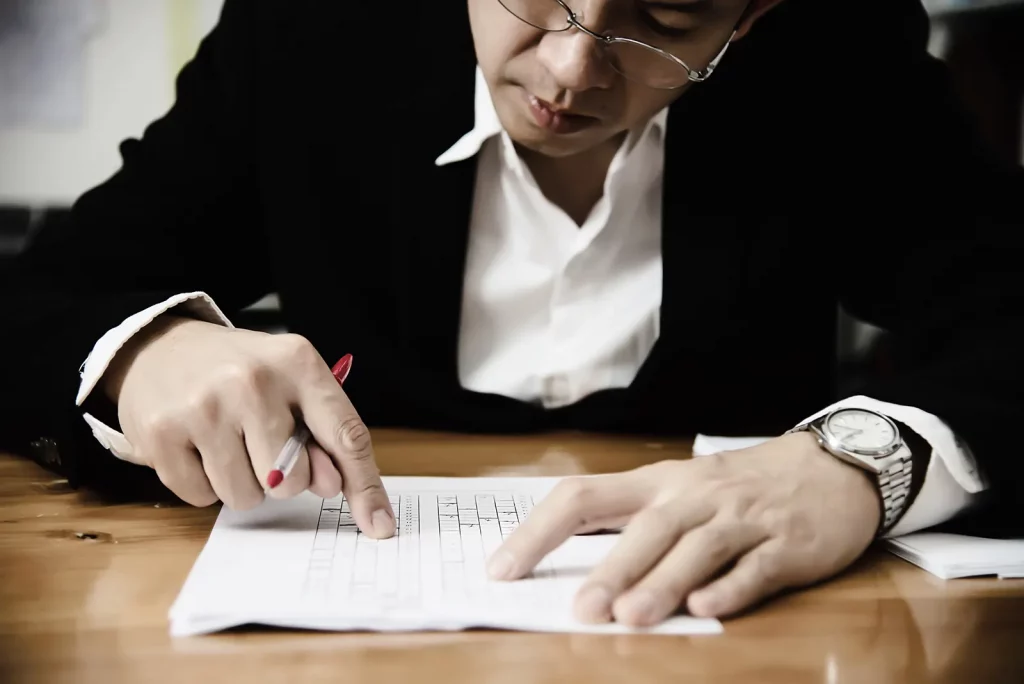 business man with glasses and silver watch analyzing a notary exam paper