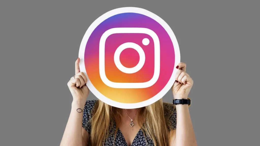 Woman wearing a floral shirt holding up an Instagram logo. How Instagram Can Help Your Notary Business to Thrive