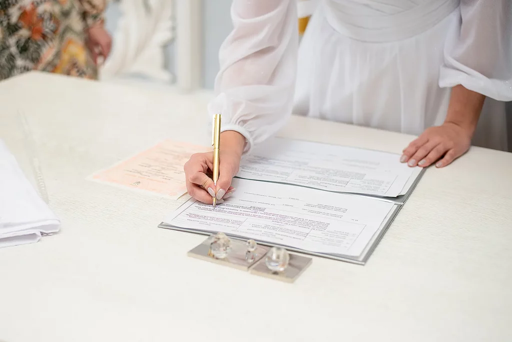 lady in a white dress signing wedding notary