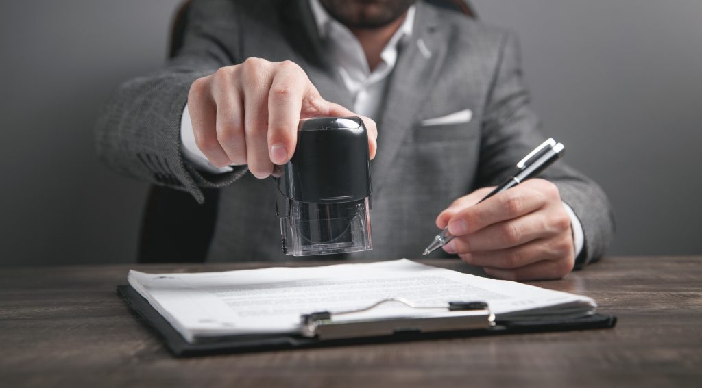 Businessman puts a stamp on the documents in the office. How to become a legal notary