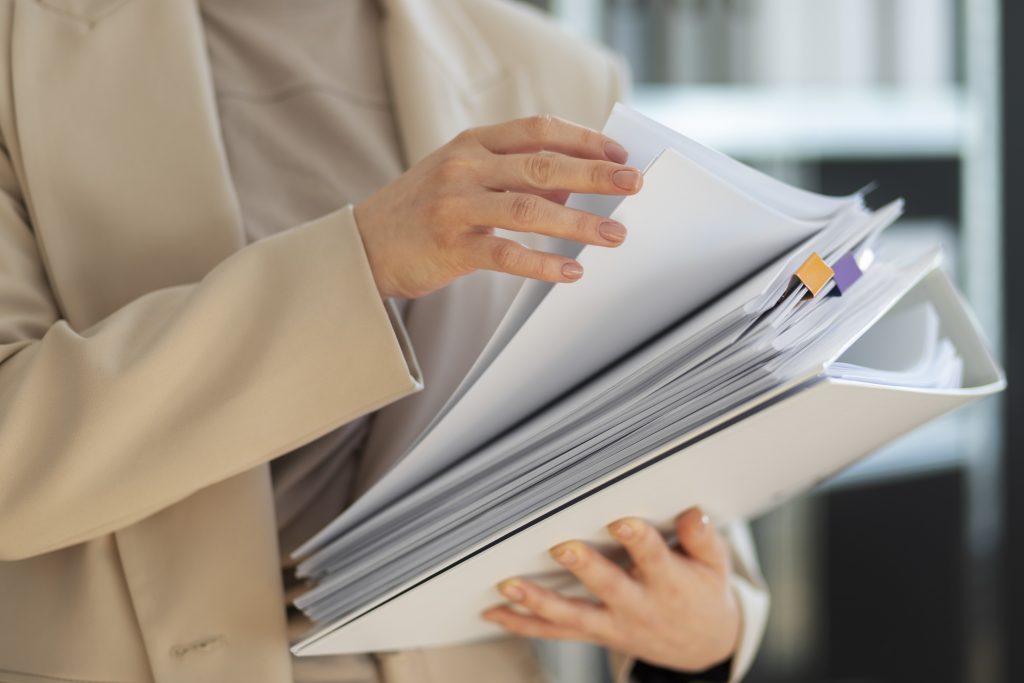 person wearing beige holding post-dated notary documents